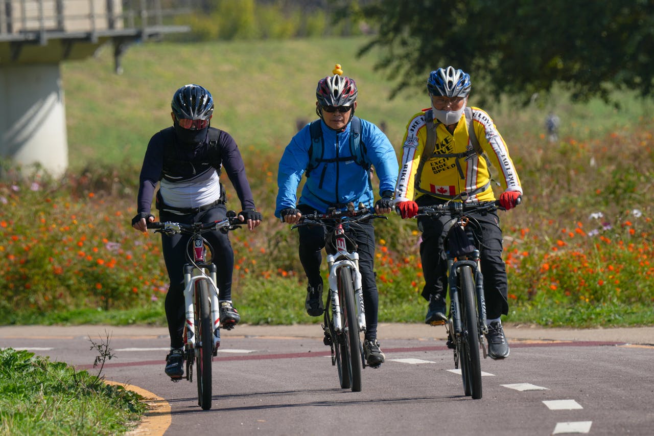 about-me-02 Three men cycling with helmets on a sunny day, showcasing outdoor activity and health.