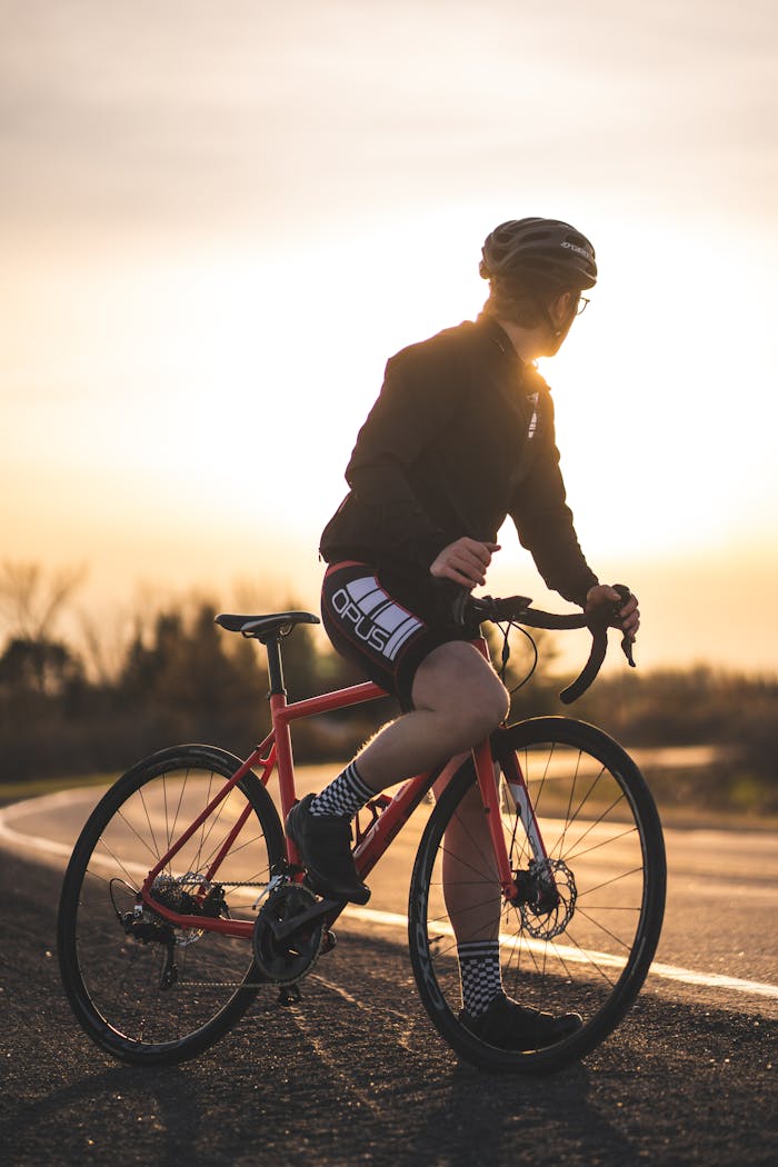 services-03 A cyclist riding a red bicycle during sunset in Ottawa, wearing a helmet and black jacket.